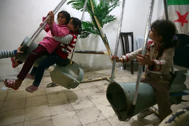 Children ride on makeshift swings made from remnants of rockets at a basement in the Duma neighbourhood in Damascus, on the second day of Eid al-Adha October 16, 2013. (Photo by Bassam Khabieh/Reuters)