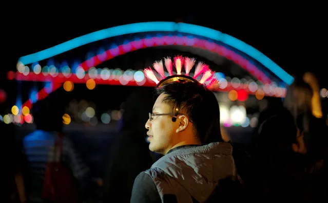 A man is seen wearing a flashing colored light headwear alongside the illuminated Sydney Harbour Bridge during the opening night of the annual Vivid Sydney light festival in Sydney, Australia May 27, 2016. (Photo by Jason Reed/Reuters)