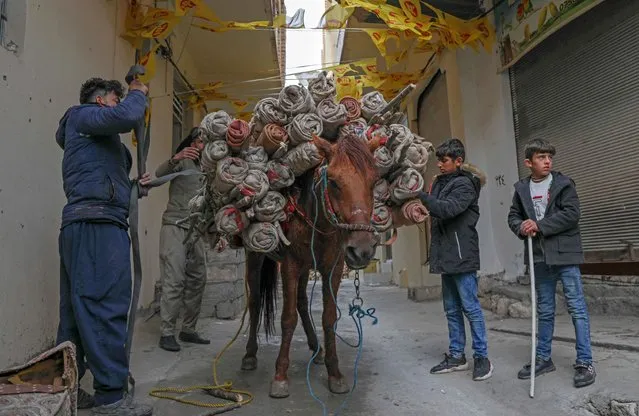 Men use a horse to transport torches during celebrations of the Persian new year Nowruz (Noruz) in the town of Akra, about 100 kilometres north of Arbil, in Iraq's northern autonomous Kurdish region on March 20, 2022. The Persian New Year is an ancient Zoroastrian tradition celebrated by Iranians and Kurds which coincides with the vernal (spring) equinox and is calculated by the solar calendar. (Photo by Safin Hamed/AFP Photo)