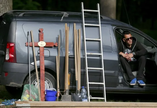 A gravedigger sits in his vehicle as he waits for the start of the first Hungarian grave digging championship, part of an international event in Debrecen, Hungary, June 3, 2016. Thirteen pairs of gravediggers are competing for the national crown, awarded based on accuracy, speed, and aesthetic quality. (Photo by Laszlo Balogh/Reuters)