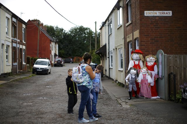 Visitors look at a family of scarecrows during the Scarecrow Festival in Heather, Britain July 29, 2015. The annual event asks residents of Heather to make scarecrows to raise thousands of pounds for local groups and charities. (Photo by Darren Staples/Reuters)