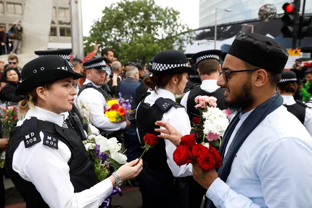 A man hands a flowers to a police officer during a gathering south of London Bridge in London, on June 7, 2017, following the June 3 terror attack on London Bridge and Borough Market British police confirmed on June 7 that the death toll from last weekend' s terror attack in London had risen from seven to eight, after announcing a body had been recovered from the River Thames. (Photo by Odd Andersen/AFP Photo)