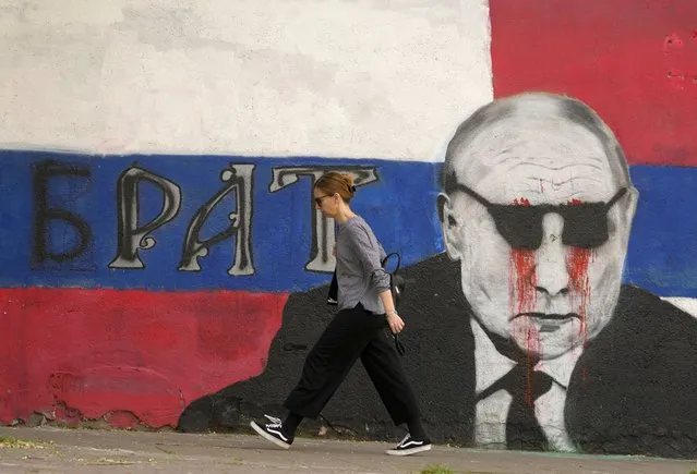 A woman passes by a mural depicting the Russian President Vladimir Putin that reads: “Brother” vandalized with paint, in Belgrade, Serbia, Saturday, May 7, 2022. Despite having to pay a big price Serbia for not introducing sanctions to Russia, Serbia will not do it, Serbian President Vucic said, but despite that the country will stay on its path toward the EU. (Photo by Darko Vojinovic/AP Photo)