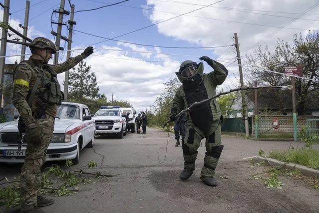 A de-miner wearing protective gear works in an area where unexploded devices were found after shelling of Russian forces in Maksymilyanivka, Ukraine, Tuesday, May 10, 2022. (Photo by Evgeniy Maloletka/AP Photo)