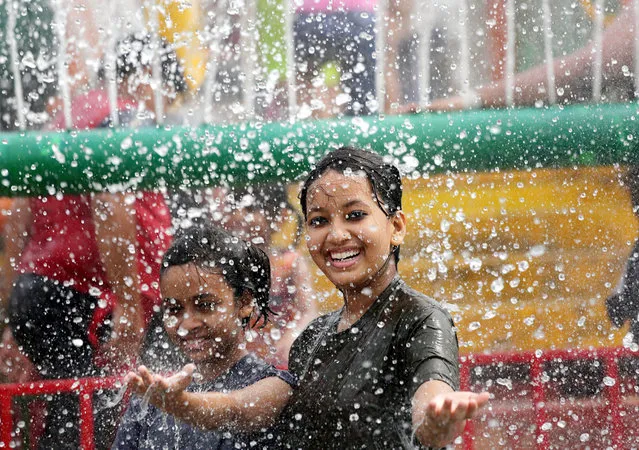An Indian girl smiles under a water splash at a water park as the temperatures reached 38 degree Celsius in Calcutta, eastern India, 12 June 2016. The summer or pre-monsoon season lasts from March to July in eastern India with the highest day temperatures ranging from 38 to 45 degrees Celsius. (Photo by Piyal Adhikary/EPA)