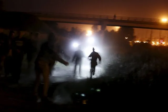 Migrants are illuminated by police torches as they run to cross a fence during an attempt to access the Channel Tunnel in Frethun, near Calais, France, August 5, 2015. (Photo by Juan Medina/Reuters)