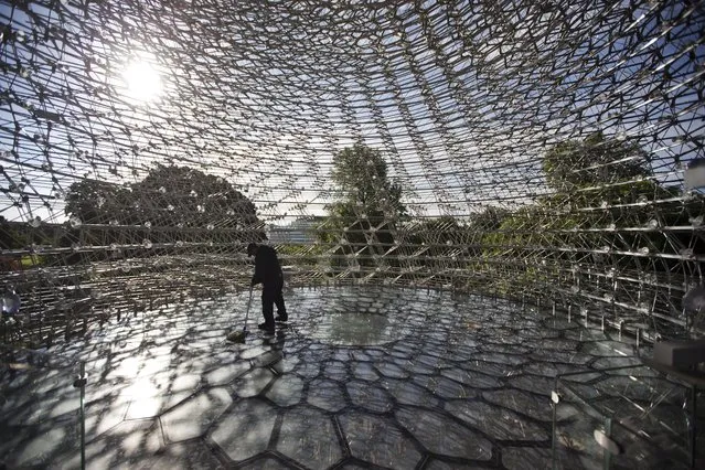 A worker cleans the floor of British artist Wolfgang Buttress' 17 metre high bee health inspired “The Hive” aluminum installation as it stands on display after being put up in Kew Royal Botanic Gardens west London, Wednesday, June 15, 2016. The installation is fitted with LED lights and a unique sound accompaniment that respond to the real-time activity of bees in a beehive behind the scenes. The sound and light intensities change as the energy levels in the real beehive surge, giving visitors an insight into life inside a bee colony. (Photo by Matt Dunham/AP Photo)