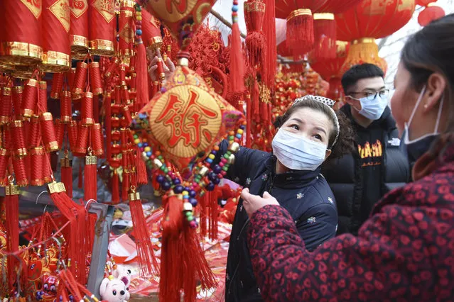 People wear face masks as they shop for decorations for the upcoming Lunar New Year, the Year of the Rat, at a market in Fuyang in central China's Anhui Province, Friday, January 24, 2020. China is swiftly building a hospital dedicated to treating patients infected with a new virus that has killed 26 people, sickened hundreds and prompted unprecedented lockdowns of cities home to millions of people during the country's most important holiday. (Photo by Chinatopix via AP Photo)