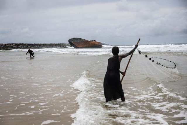 Fisherwoman throw a net close to a stranded old vessel off Tarkwa Bay in Lagos on September 28, 2024. (Photo by Olympia de Maismont/AFP Photo)