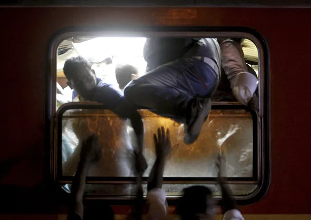 Migrants try to board a train that would take them towards Serbia, at the railway station in the southern Macedonian town of Gevgelija, on Wednesday, August 12, 2015. (Photo by Boris Grdanoski/AP Photo)