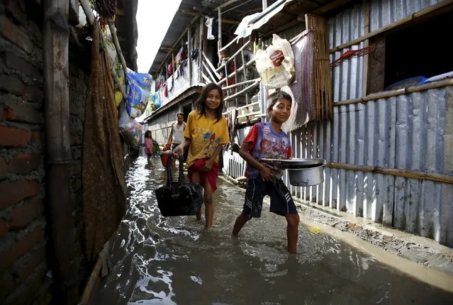 Children holding their belongings walk along an alley after floodwaters caused by heavy rainfall flowing from the swollen Bagmati River entered a slum in Kathmandu, Nepal August 17, 2015. (Photo by Navesh Chitrakar/Reuters)