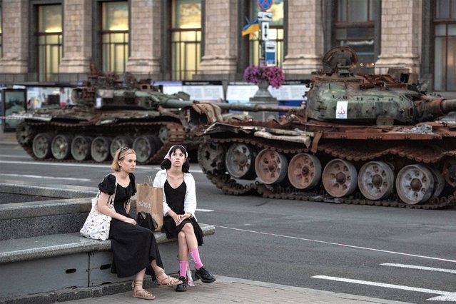 Young women talk as they sit on the bench next to the destroyed Russian military vehicles on August 23, 2023 in Kyiv, Ukraine. Ukraine celebrates Independence Day on August 24, and also marks eighteen months since the beginning of Russia's ongoing war in Ukraine. (Photo by Alexey Furman/Getty Images)