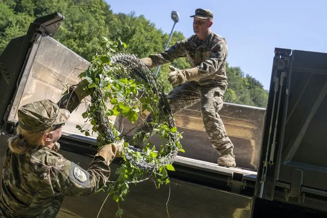 A Slovenian soldier deployed for the removal of border fence load razor wire on a truck at the border crossing with Croatia in Krmacina, Slovenia, Friday, July 15, 2022. Slovenian army has started to remove the razor wire fence on the border with Croatia that was put up to curb migrant crossing after more than a million people fleeing violence and poverty entered Europe in a huge migration wave in 2015. (Photo by Darko Bandic/AP Photo)