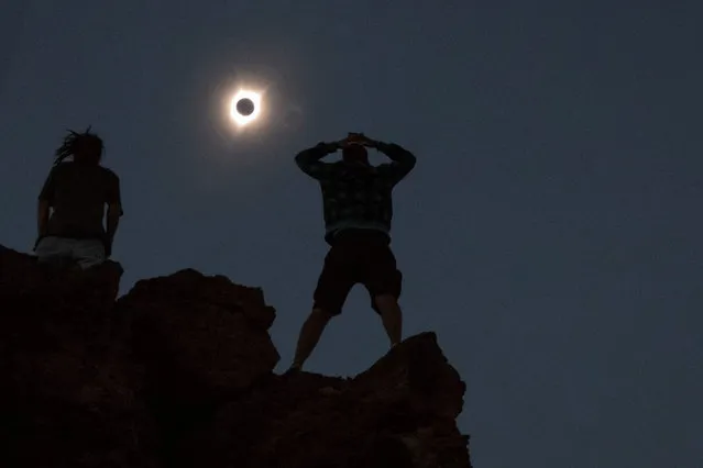 Enthusiasts watch while standing atop Carroll Rim Trail at Painted Hills, a unit of the John Day Fossil Beds National Monument, near Mitchell, Oregon on August 21, 2017. (Photo by Adrees Latif/Reuters)