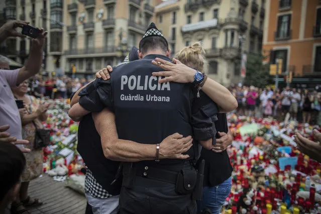 In this Monday, August 21, 2017 file photo, a policeman hugs a boy and his family that he helped during the terrorist attack, at a memorial to the victims on Las Ramblas, Barcelona, Spain. (Photo by Santi Palacios/AP Photo)