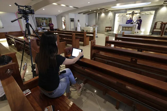 Catholic priest Rymond Ratilla presides over a mass that is live video streamed on their Facebook page at an empty Chapel of the Nativity of the Blessed Virgin Mary in Cubao, Quezon city, Philippines, Sunday, March 15, 2020. Mass was suspended at all churches in the capital to avoid large gatherings as part of precautionary measures against the spread of the new coronavirus in this largely Roman Catholic country. For most people, the new coronavirus causes only mild or moderate symptoms. For some, it can cause more severe illness, especially in older adults and people with existing health problems. (Photo by Aaron Favila/AP Photo)