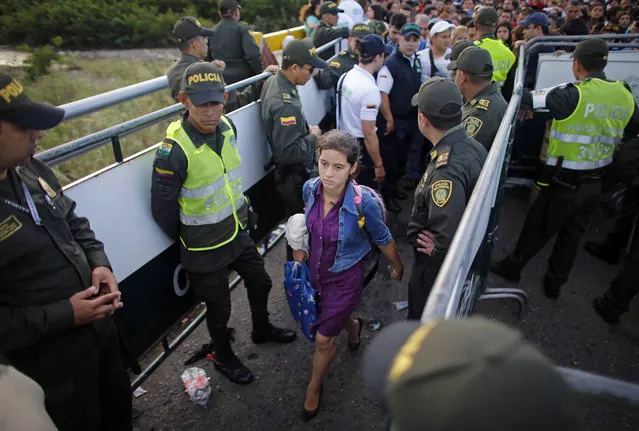 Colombian policemen stand as a Venezuelan woman crosses into Colombia through the Simon Bolivar bridge linking San Antonio del Tachira, Venezuela, with Cucuta, Colombia, to buy supplies, Sunday, July 17, 2016. (Photo by Ariana Cubillos/AP Photo)