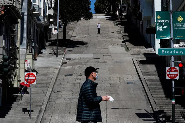 People walk on the streets, a day after California's Governor Gavin Newsom implemented a statewide “stay at home order” directing the state's nearly 40 million residents to stay in their homes for the foreseeable future in the face of the fast-spreading coronavirus disease (COVID-19), in San Francisco, California, U.S. March 20, 2020. (Photo by Shannon Stapleton/Reuters)