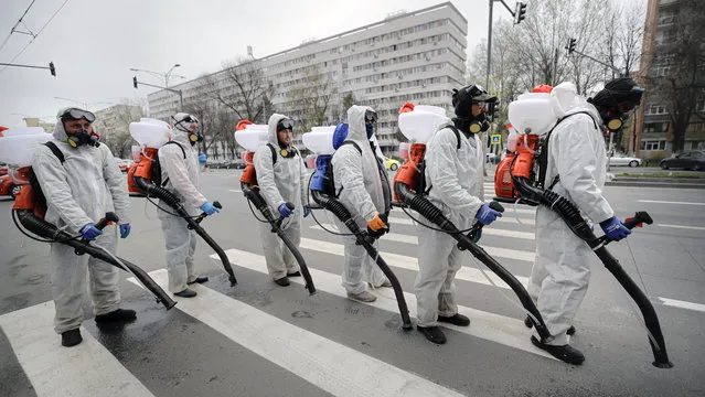 Municipal workers wearing protective outfits wait to reload the tanks with chemicals while disinfecting an area of the Romanian capital Bucharest, Romania, Tuesday, March 31, 2020 as authorities attempt to limit the spread of the new coronavirus. (Photo by Vadim Ghirda/AP Photo)