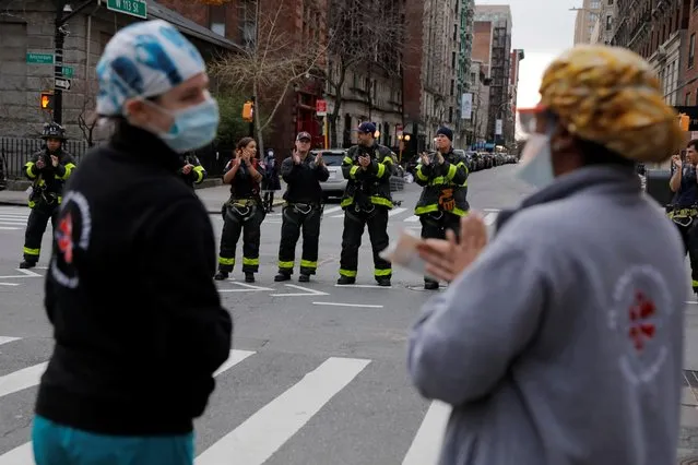 Members of the Ladder 22 and Engine 76 fire crews of the New York Fire Department clap for health and medical workers from the Mount Sinai Morningside hospital at 7:00PM, during the coronavirus disease (COVID-19) outbreak in Manhattan, New York City, U.S. April 2, 2020. (Photo by Andrew Kelly/Reuters)