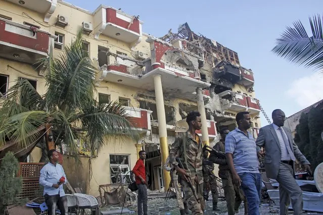Security forces and others walk in front of the damaged Hayat Hotel in the capital Mogadishu, Somalia Sunday, August 21, 2022. Somali authorities on Sunday ended a deadly attack in which at least 20 people were killed and many others wounded when gunmen from the Islamic extremist group al-Shabab, which has ties with al-Qaida, stormed the Hayat Hotel in the capital on Friday evening. (Photo by Farah Abdi Warsameh/AP Photo)