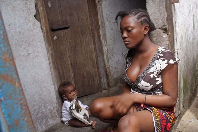 A woman sits with a baby, in the West Point area that has been hardest hit by the Ebola virus spreading in Monrovia, Liberia, Monday, August 25, 2014. A Liberian doctor who was among three Africans to receive an experimental Ebola drug has died, the country's information minister said Monday. (Photo by Abbas Dulleh/AP Photo)