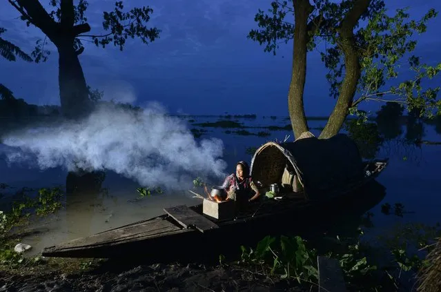An Indian woman prepares dinner in her country boat after her village was submerged in flood waters in the flood affected Morigaon district of Assam, India, 26 July 2016. Over half a million people of 15 districts in Assam state have been affected by the current wave of floods. According to the media reports more than 70 relief camps have been set up in the affected districts to provide shelter to the flood affected people. (Photo by EPA/Stringer)