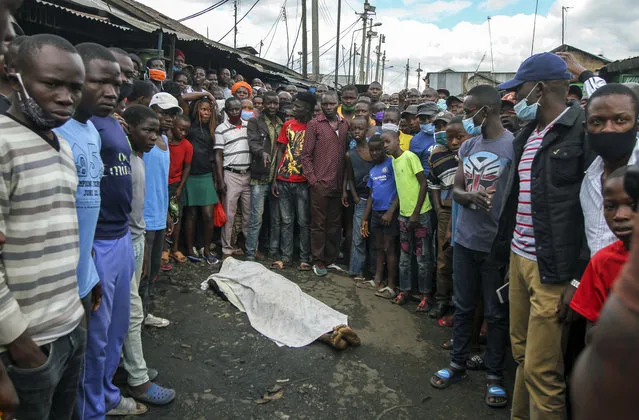 Residents gather around the covered dead body of a man, who they claimed had been beaten by police for being outside during the dusk to dawn curfew, but which could not be independently verified, in the Mathare slum, or informal settlement, of Nairobi, Kenya Monday, May 4, 2020. Human rights groups have protested the police use of excessive force to enforce the curfew put in place to curb the spread of the new coronavirus. (Photo by AP Photo/Stringer)