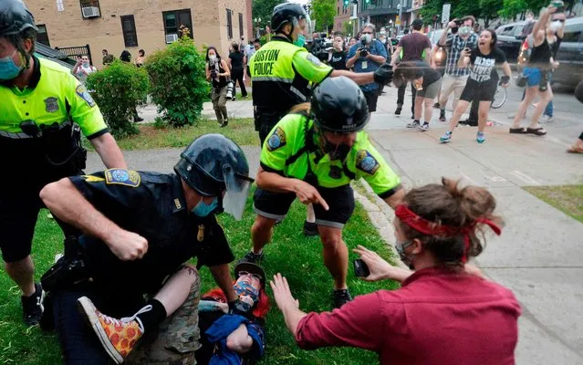 A police officer (L) holds down a protester while another (back) sprays pepper spray as they clash outside the District Four Police station during a Black Lives Matter protest against police brutality and racism in the US, including the recent deaths of George Floyd, Ahmaud Arbery, Breonna Taylor, in Boston, Massachusetts, on May 29, 2020. The Minneapolis police officer accused of killing George Floyd, a handcuffed African American man, was charged with murder on May 29 as authorities declared a curfew after three nights of violent protests left parts of the city in flames. (Photo by Joseph Prezioso/AFP Photo)