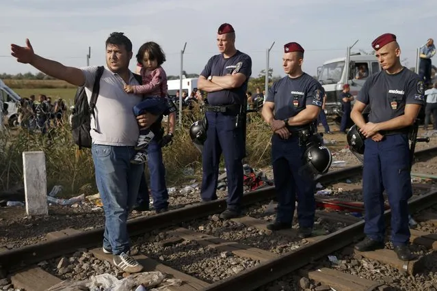 A migrant with his child talks to the police officers after Hungarian police sealed the border with Serbia near the village of Horgos, Serbia, September 14, 2015, near the Hungarian migrant collection point in Roszke. (Photo by Marko Djurica/Reuters)