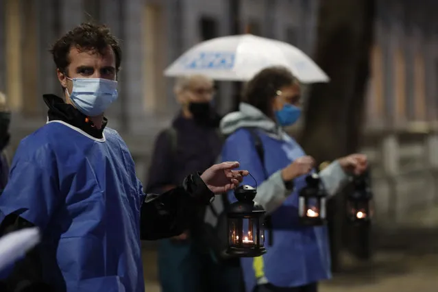 Campaigners hold lanterns outside Downing Street for British NHS medical and care workers who have died due to COVID-19, in London, Friday, July 3, 2020. A number of NHS staff and campaigners carried one lantern to represent people who have died due to COVID-19, as they walked from St. Thomas' Hospital over Westminster Bridge to then hold a candlelit vigil outside Downing Street, where they read out a small number of representative names of NHS staff who died. (Photo by Alastair Grant/AP Photo)