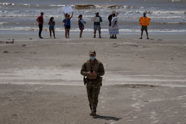 A police officer walks away from local residents protesting closed beaches on the 4th of July amid the global outbreak of the coronavirus disease (COVID-19) in Galveston, Texas, U.S., July 4, 2020. (Photo by Adrees Latif/Reuters)