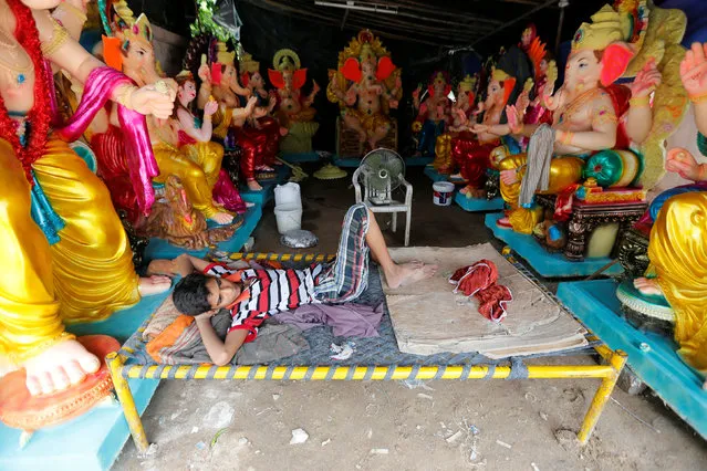 A vendor selling idols of Hindu god Ganesh, the deity of prosperity, rests as he waits for customers at a roadside workshop in Ahmedabad, India, August 29, 2016. (Photo by Amit Dave/Reuters)