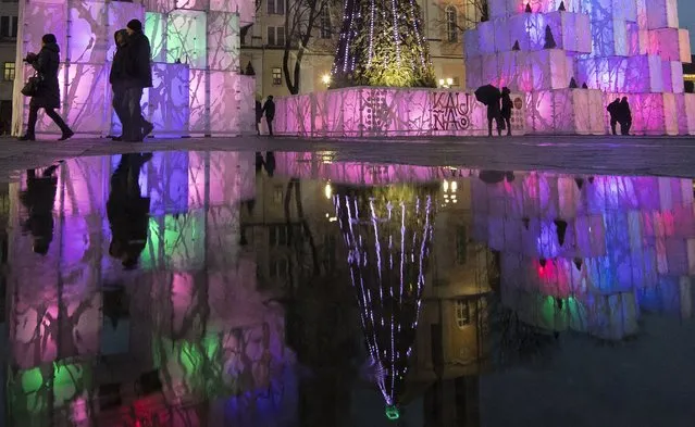 Visitors walk in front of the illuminated Christmas tree in the Old city in Kaunas, Lithuania, Thursday, December 7, 2017. Kaunas is the second largest city in Lithuania. (Photo by Mindaugas Kulbis/AP Photo)