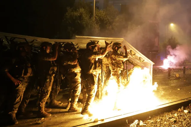 Molotov cocktails are hurled at Lebanese soldiers by anti-government protesters during a protest against the political elites and the government after this week's deadly explosion at Beirut port which devastated large parts of the capital in Beirut, Lebanon, Saturday, August 8, 2020. (Photo by Hassan Ammar/AP Photo)