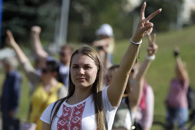 A woman gestures as she and other people gather to pay the last respect a protester who died amid the clashes with police, in Minsk, Belarus, Tuesday, August 11, 2020. Thousands of opposition supporters who also protested the results met with a tough police crackdown in Minsk and several other Belarusian cities for two straight nights. Belarus' health officials said over 200 people have been hospitalized with injuries following the protests, and some underwent surgery. (Photo by Sergei Grits/AP Photo)
