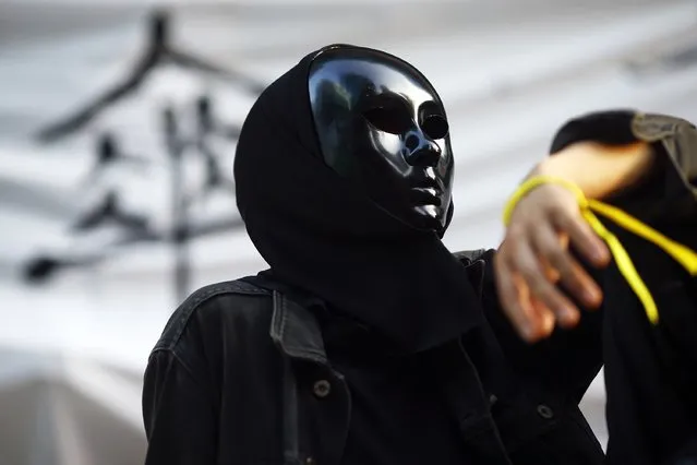 A pro-democracy protester wears a mask as he monitors barricades set-up in Mongkok shopping district in Hong Kong October 30, 2014. A member of China's central bank's advisory body warned on Wednesday that Beijing will punish Hong Kong if pro-democracy protests that have paralyzed parts of the Chinese-controlled financial center for a month are allowed to continue. The Chinese character in the background means “umbrella”. (Photo by Damir Sagolj/Reuters)