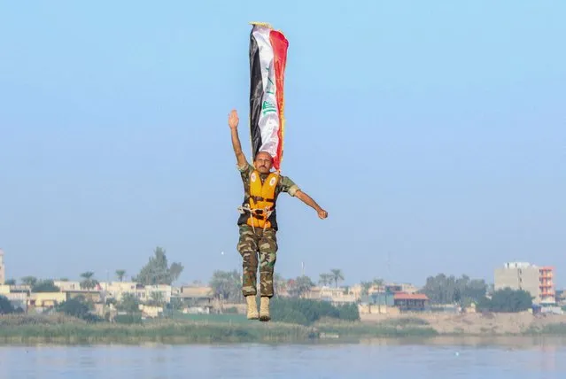 An Iraqi army cadet performs “the leap of faith” from a bridge in Baghdad, Iraq on December 3, 2022. (Photo by Ahmed Saad/Reuters)