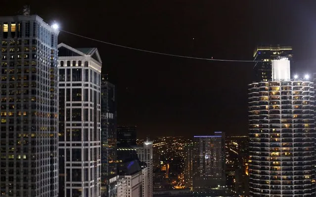 Daredevil Nik Wallenda walks along a tightrope between two skyscrapers suspended 500 feet (152.4 meters) above the Chicago River in Chicago, Illinois, November 2, 2014. (Photo by Jim Young/Reuters)