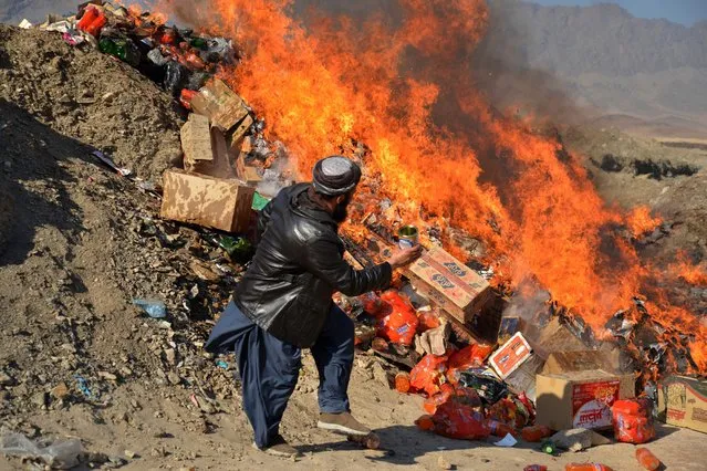 A local goverment official burns expired food items removed from shops on the outskirts of Kandahar on December 14, 2022. (Photo by AFP Photo/Stringer)