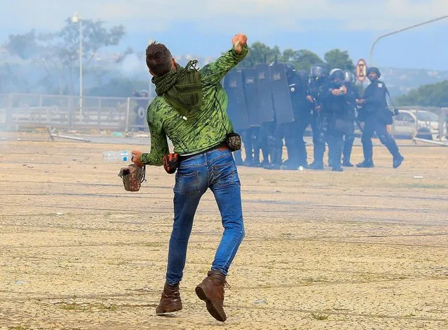 A supporter of Brazilian former President Jair Bolsonaro throws stones at security forces during clashes outside Planalto Presidential Palace in Brasilia on January 8, 2023. Brazilian police used tear gas Sunday to repel hundreds of supporters of far-right ex-president Jair Bolsonaro after they stormed onto Congress grounds one week after President Luis Inacio Lula da Silva's inauguration, an AFP photographer witnessed. (Photo by Sergio Lima/AFP Photo)