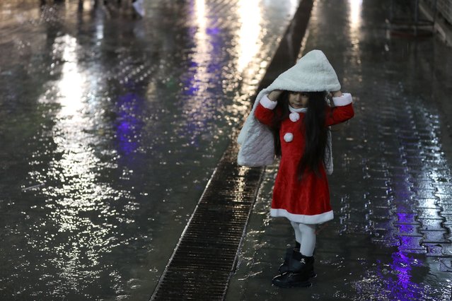 A Palestinian child wearing a Santa Claus under heavy rain during Christmas eve service at the Roman Catholic Church of the Holy Family in Gaza City on December 24, 2022. (Photo by Majdi Fathi/NurPhoto via Getty Images)