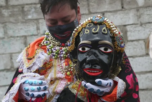 Luis Chacon, the person playing the character of Mama Negra takes a break during the festival in honor of the Virgin of Las Mercedes in Latacunga, Ecuador, Thursday, September 24, 2020. The Mama Negra festival dates back to 1742 when the people of Latacunga ask the Virgin of Las Mercedes to protect them from the eruptions of the neighboring Cotopaxi volcano. Today the festival took place despite the new coronavirus pandemic restrictions and devotees asked the virgin to protect them from the disease. (Photo by Dolores Ochoa/AP Photo)