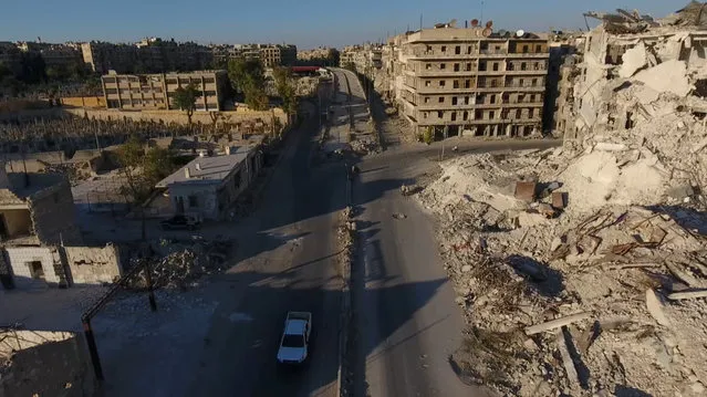 A still image taken on September 27, 2016 from a drone footage obtained by Reuters shows a vehicle driving past damaged buildings in a rebel-held area of Aleppo, Syria. (Photo by Reuters TV)