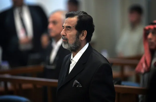 Saddam Hussein stands as an unseen witness is sworn in for testimony during his trial in Baghdad's heavily fortified Green Zone, in Iraq, on October 19, 2006. Saddam and six other co-defendants faced charges of war crimes and crimes against humanity for their roles in Operation Anfal, a military offensive against the Kurds in 1987–88. (Photo by David Furst/AP Photo/The Atlantic)