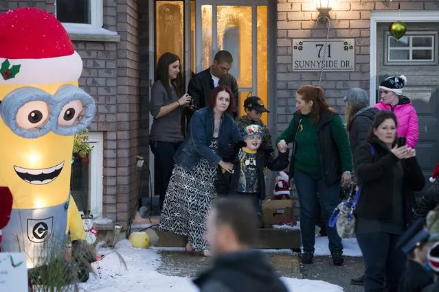 Evan Leversage, who is terminally ill with brain cancer, leaves his house to get a tour of the neighbourhood to see all the Christmas lights with his mother Nicole Wellwood (2nd L, front) in St. George, Ontario, Canada October 24, 2015. (Photo by Mark Blinch/Reuters)