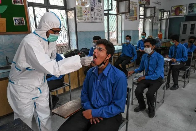 A health official (L) collects a swab sample from a student to test for the Covid-19 coronavirus at a government school in Lahore on October 1, 2020, after the educational institutes reopened nearly six months after the spread of the Covid-19 coronavirus. (Photo by Arif Ali/AFP Photo)