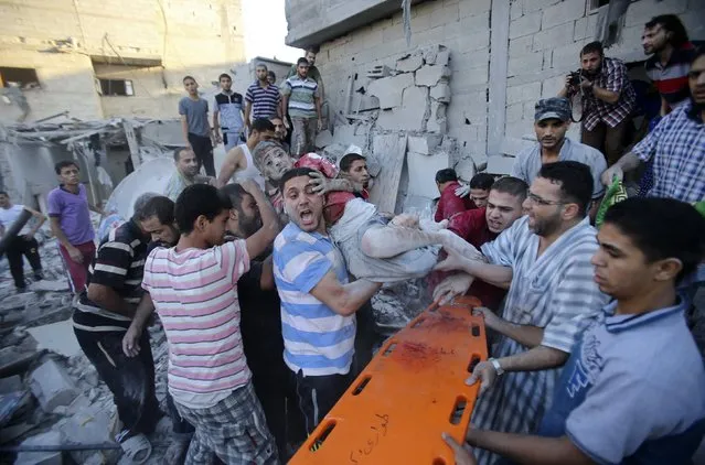 Palestinians carry a wounded boy who was evacuated from under the rubble of a house, which witnesses said was destroyed in an Israeli air strike, in Rafah in the southern Gaza Strip, in this August 3, 2014 file photo. (Photo by Ibraheem Abu Mustafa/Reuters)