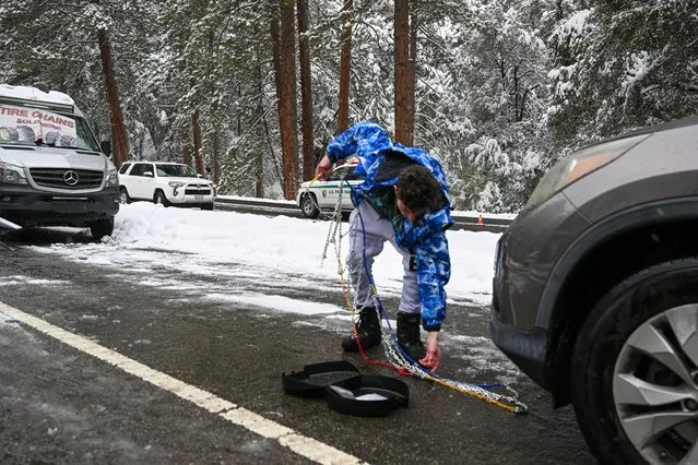 A man installs tire chain on his car as snow blankets Yosemite National Park in California, United States on February 23, 2023 as winter storm alerted in California. (Photo by Tayfun Coskun/Anadolu Agency via Getty Images)