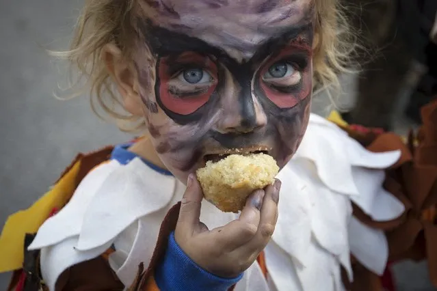 A child dressed as a bird takes a bite of a muffin as she takes part in the Children's Halloween day parade at Washington Square Park in the Manhattan borough of New York October 31, 2015. (Photo by Carlo Allegri/Reuters)